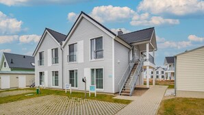 A two-story house with a balcony, a staircase, and a paved driveway.
