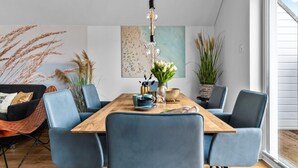 A dining area with a wooden table, blue chairs, and a hanging light fixture.