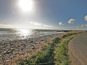 A coastal road with a rocky beach and a clear sky.