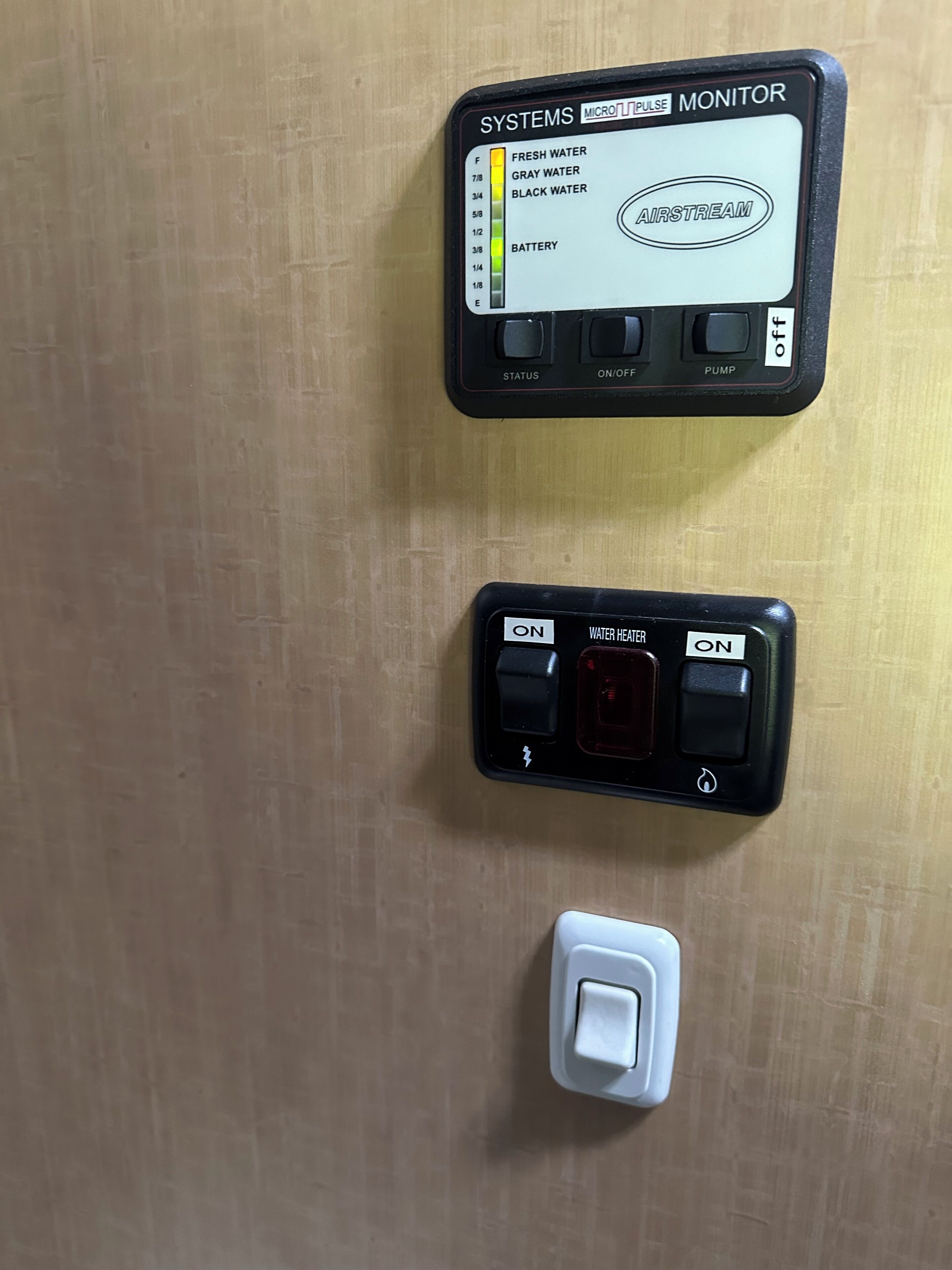 A water quality monitor and a water heater control panel on a wooden wall.