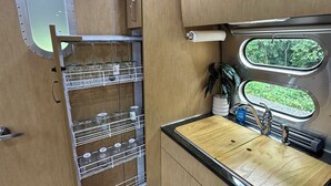 Cocina compacta con encimera de madera, un lavabo y una ventana con vistas a la vegetación.