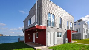 A modern two-story building with a red entrance and a balcony. - Awesome home in Olpenitz with sauna (Olpenitz)