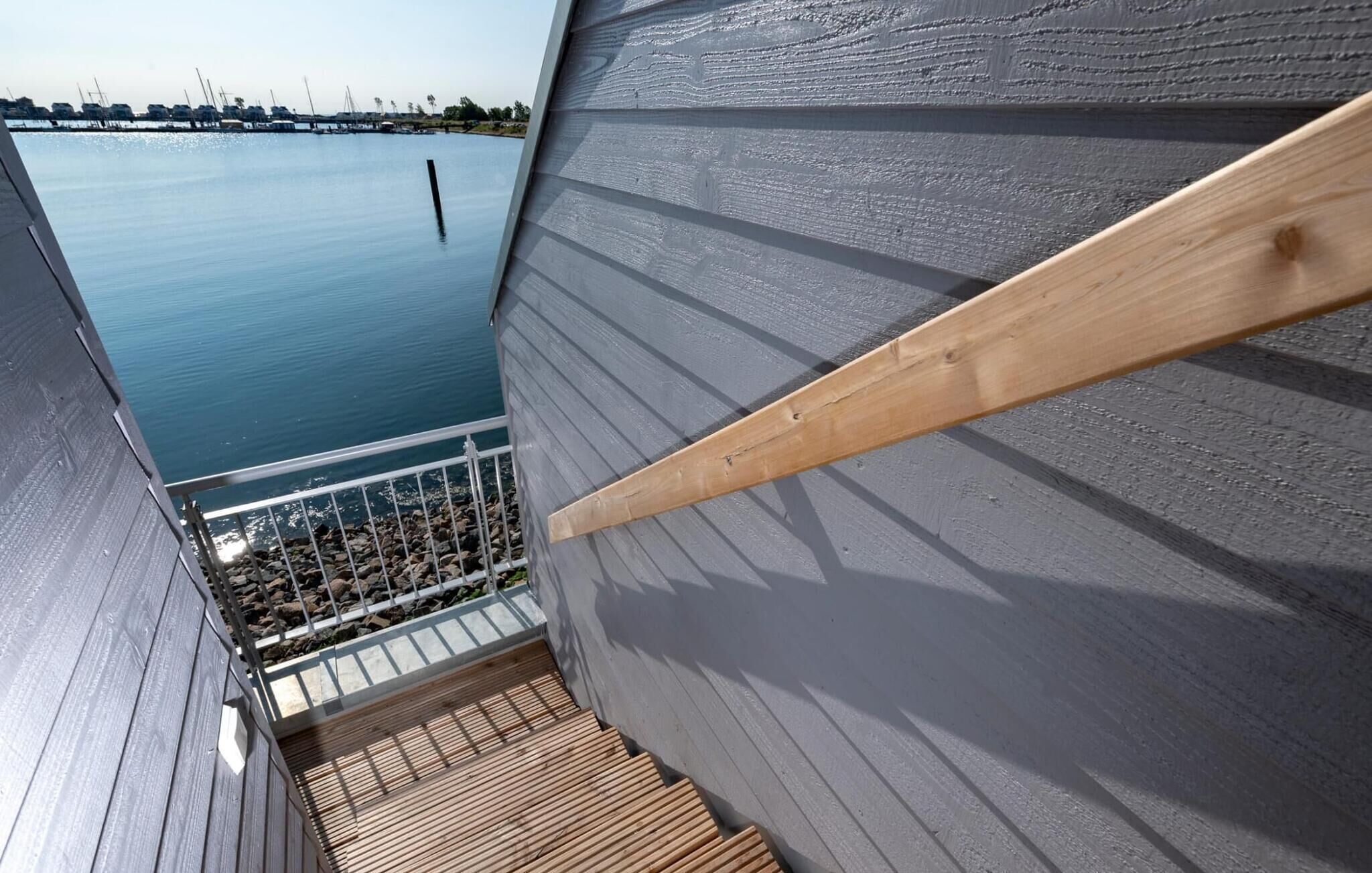 A wooden deck with a view of calm water and boats.