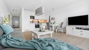 A modern living room with a sofa, a dining table, and a TV. - Nice apartment in Olpenitz with WiFi (Olpenitz)
