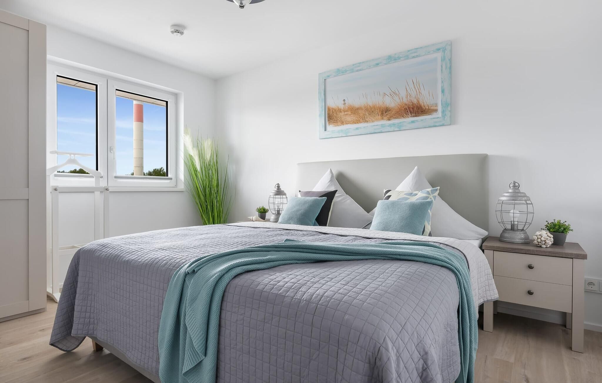 Une chambre à coucher avec un grand lit, une table de chevet, une fenêtre donnant sur un beau paysage et un tableau accroché au mur.
