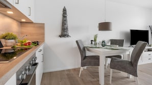 A modern kitchen with a wooden countertop, a built-in oven, and a dining area with a white table and grey chairs. - Nice apartment in Olpenitz with WiFi (Olpenitz)