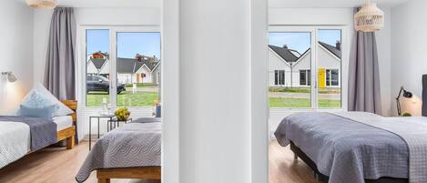 A modern bedroom with a large window, a bed, a bedside table, and a lamp.