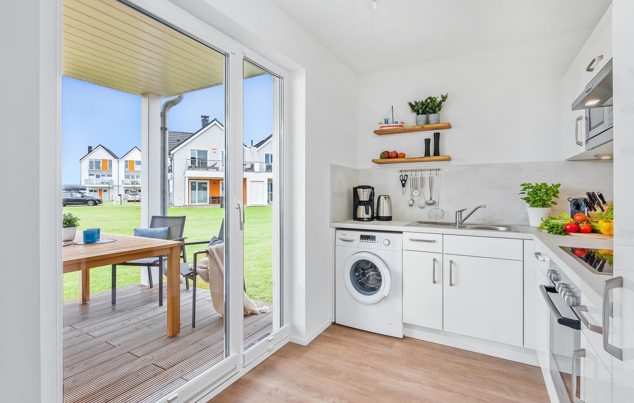Una cocina moderna con lavadora, un lavamanos y una zona de comedor con mesa y sillas.