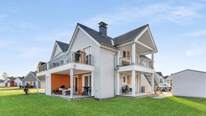 A two-story house with a balcony on the upper floor, a covered porch on the ground floor, and a chimney. - Beach front apartment in Olpenitz (Olpenitz)