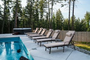 A pool area with lounge chairs and a hot tub.