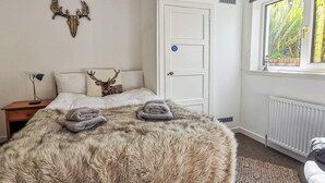 A bedroom with a large bed, a nightstand, a door with a 'Keep shut' sign, a radiator, and a window with a view of greenery. - 5 bedroom accommodation in Brodick, Isle of Arran (Brodick, Isle of Arran)
