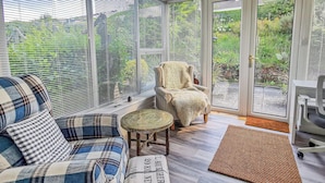 A cozy seating area with a plaid sofa, a chair, and a small round table. - 5 bedroom accommodation in Brodick, Isle of Arran (Brodick, Isle of Arran)