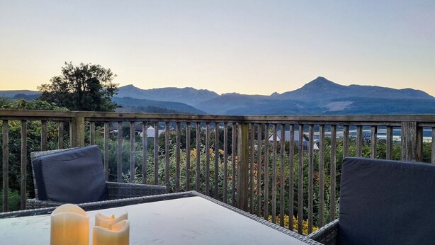 A balcony with a view of mountains, a table with candles, and wicker furniture. - 5 bedroom accommodation in Brodick, Isle of Arran (Brodick, Isle of Arran)