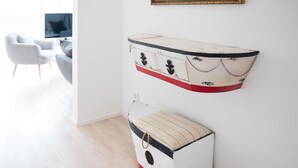 Un aparador blanco con tiradores negros y detalles rojos, ubicado frente a una pared blanca en una habitación con suelo de madera.