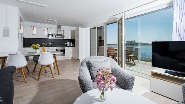 Un apartamento moderno con cocina, comedor y balcón con televisor.