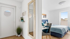A bedroom with a bed, a chair, a desk, and a mirror.