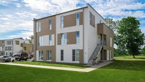 A multi-story residential building with a flat roof, large windows, and a visible staircase leading to the entrance.
