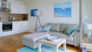 Ein modernes Wohnzimmer mit einem grauen Sofa, einem kleinen Tisch und einem blauen Teppich.