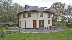 A circular building with a flat roof, a central door, and multiple windows. - 4 bedroom accommodation in Cilycwm, Llandovery (Cilycwm, Llandovery)