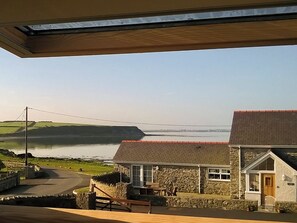 A coastal view with a stone building, a wooden deck, and a clear sky. - 4 bedroom accommodation in Llanfwrog, near Holyhead (Llanfwrog, near Holyhead)