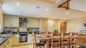 Une cuisine moderne avec des meubles en bois, une table à manger pour quatre personnes et une machine à café.