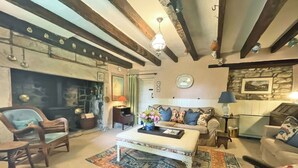 A cozy living room with a fireplace, a sofa set, a coffee table, and a patterned rug.