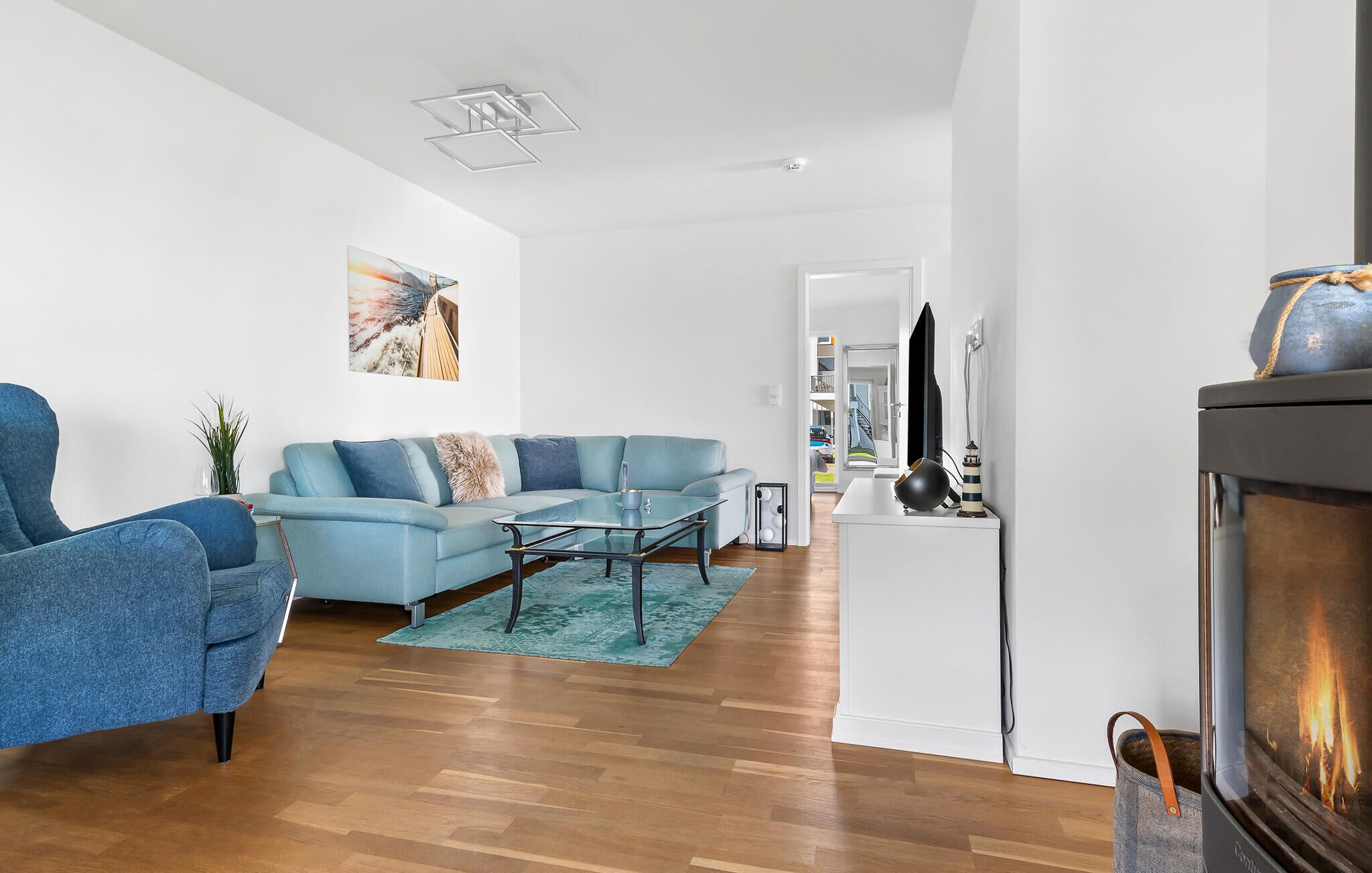 A modern living room with a blue sofa, a glass coffee table, and a fireplace.