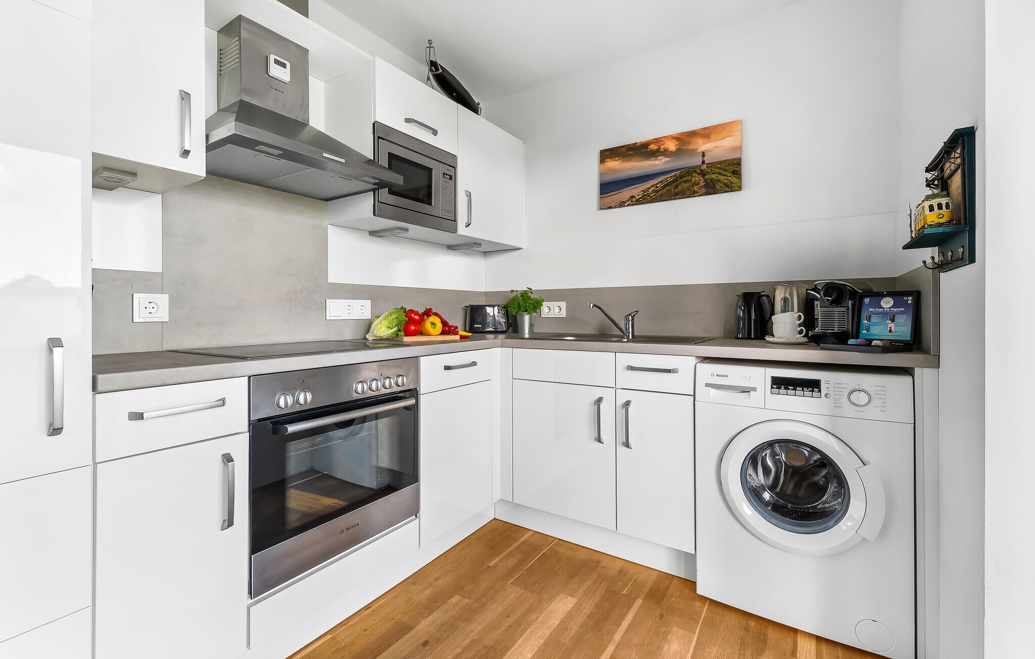 Una cocina compacta con horno Bosch, lavadora y cafetera.
