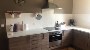 Moderni keittiö, jossa on sisäänrakennettu uuni, liesi ja kahvinkeitin.