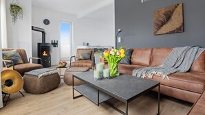 Ein modernes Wohnzimmer mit Kamin, Ledersofas, einem Couchtisch und einem großen Fenster.