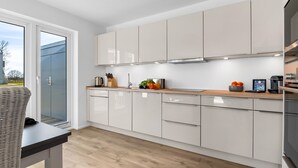 A modern kitchen with white cabinets, a wooden countertop, and a view of the outdoors.