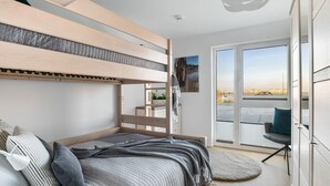 Une chambre moderne avec un lit superposé, une vue sur un plan d’eau et un balcon équipé d’une chaise.