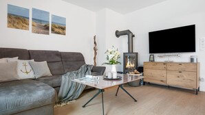 Un salon moderne avec un canapé gris, une table basse, une cheminée, un téléviseur et des meubles en bois.
