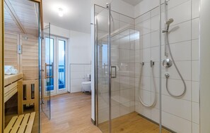 Ein modernes Badezimmer mit einer Duschkabine aus Glas, einer Holzbank und einer Toilette.