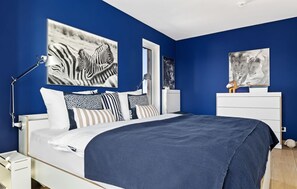 Ein Schlafzimmer mit einem Bett, einem Nachttisch, einer Lampe und Bildern an den Wänden.