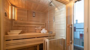 A sauna room with wooden benches, a bench seat, and a glass door leading to an outdoor area.