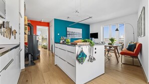 A modern kitchen with a central island, wooden flooring, and a bright teal accent wall.