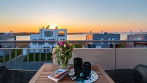 A balcony with a table, a vase of flowers, and a book.