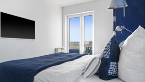 A modern bedroom with a bed, a window, and a nightstand.