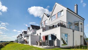A modern residential building with multiple balconies, large windows, and a flat roof.