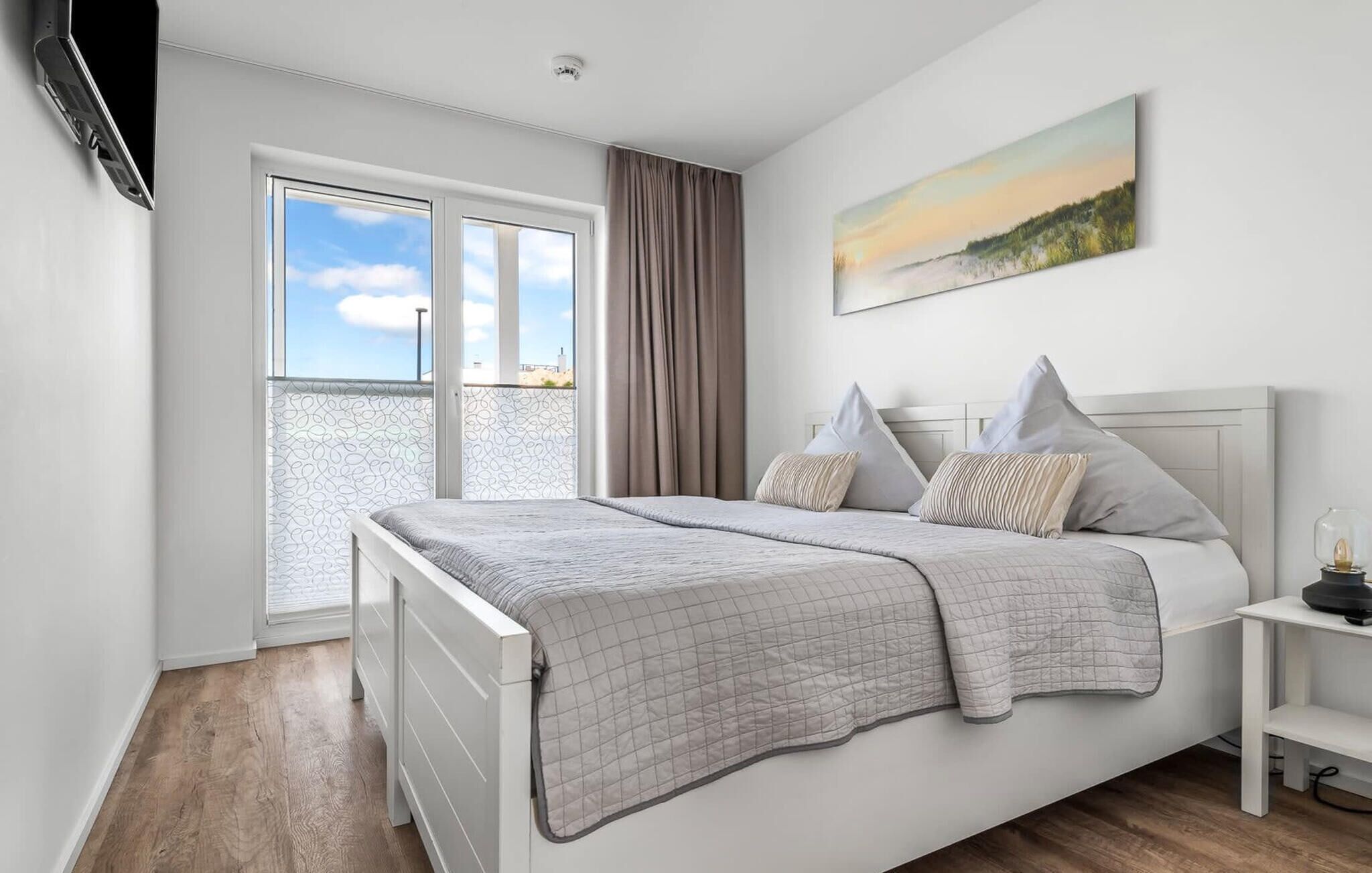 Une chambre à coucher avec un lit, une fenêtre, un tableau et une table de chevet.