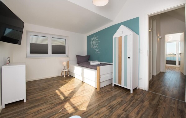A modern, well-lit room with a bed, a small table, and a TV. - Beach front home in Olpenitz with sauna (Olpenitz)