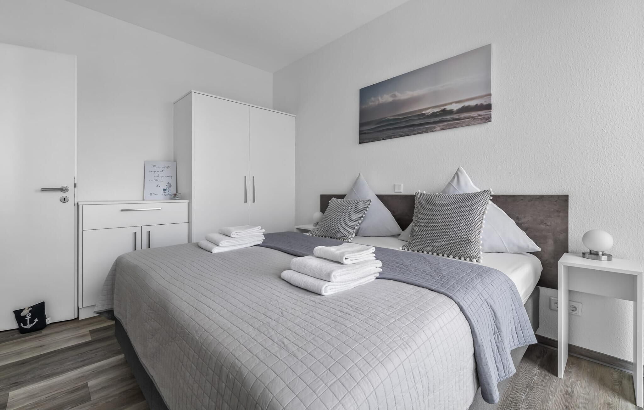 Ein modernes Schlafzimmer mit Bett, Nachttisch, Kleiderschrank und einem Bild an der Wand.