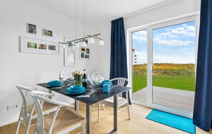 Enjoy meals in this dining area with a table for four, surrounded by framed pictures and a sliding glass door leading to a grassy outdoor space.