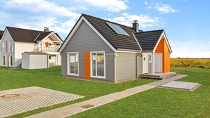 En moderne etplansvilla med grå facade, skråtag og en lille veranda.