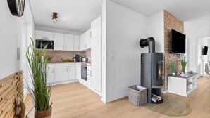 Una cucina moderna con mobili bianchi, forno a incasso e stufa a legna.
