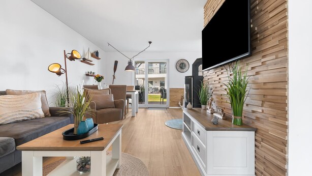 Un soggiorno moderno con un divano, un tavolino da caffè e una TV montata a parete sopra un mobile in legno.