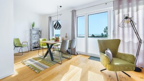 Un salon moderne avec un coin repas, de grandes fenêtres et une vue sur l’extérieur.