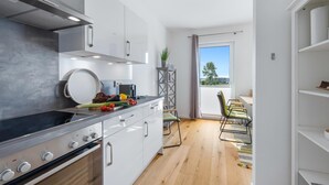 Une cuisine moderne avec des armoires blanches, une hotte de cuisinière en acier inoxydable et un plancher en bois.