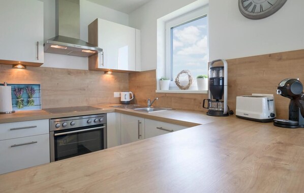 A modern kitchen with a stove, oven, sink, and coffee maker. - Amazing home in Olpenitz with sauna (Olpenitz)
